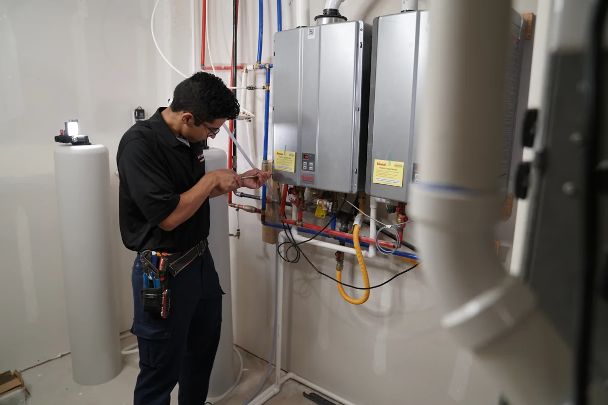 Technician working beside wall-mounted tankless water heaters